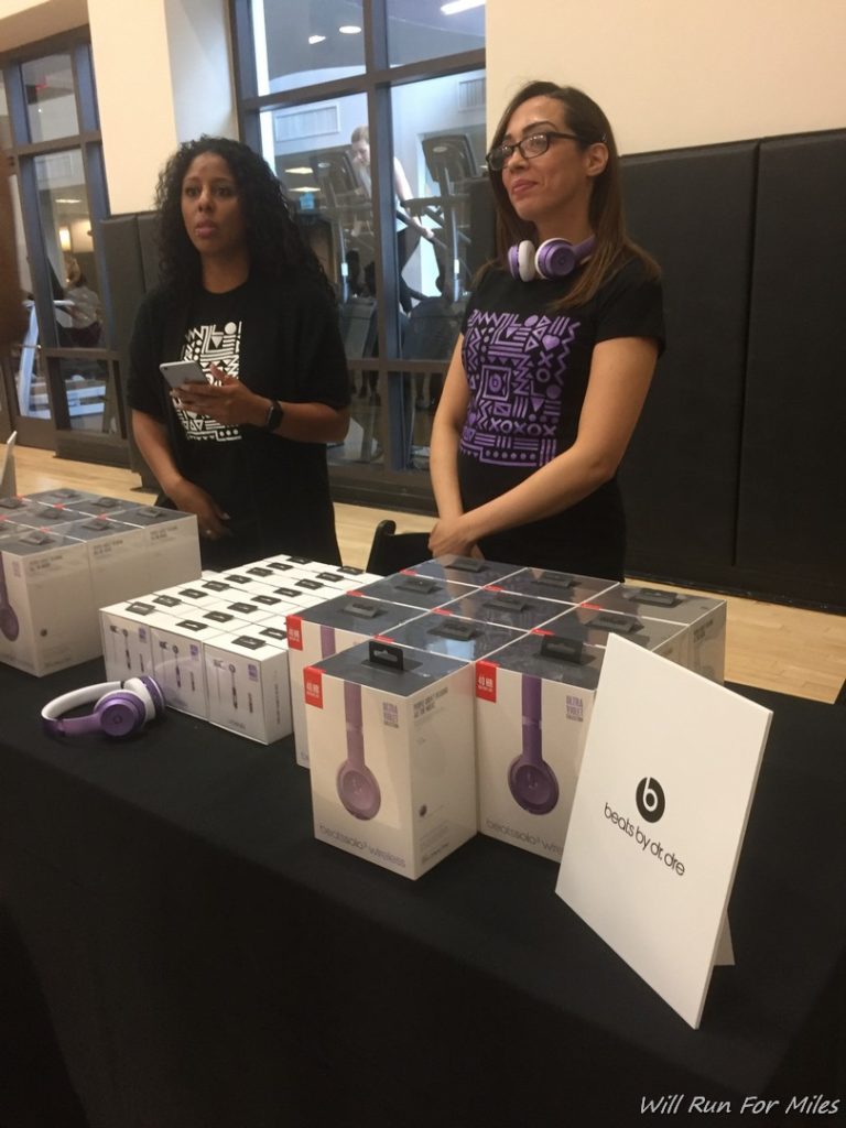 two women standing next to a table with boxes of headphones