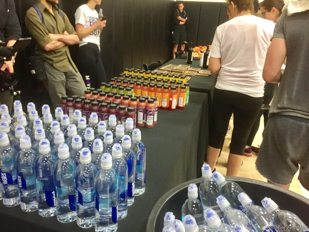 a group of people standing around a table with bottles of water
