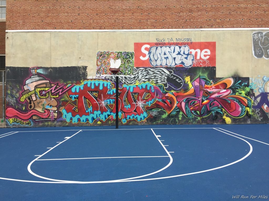 a basketball court with graffiti on the wall