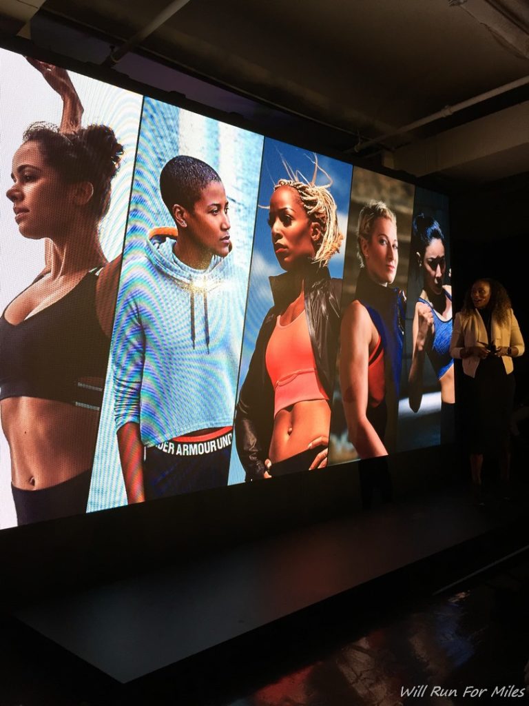 a woman standing in front of a large screen with images of women