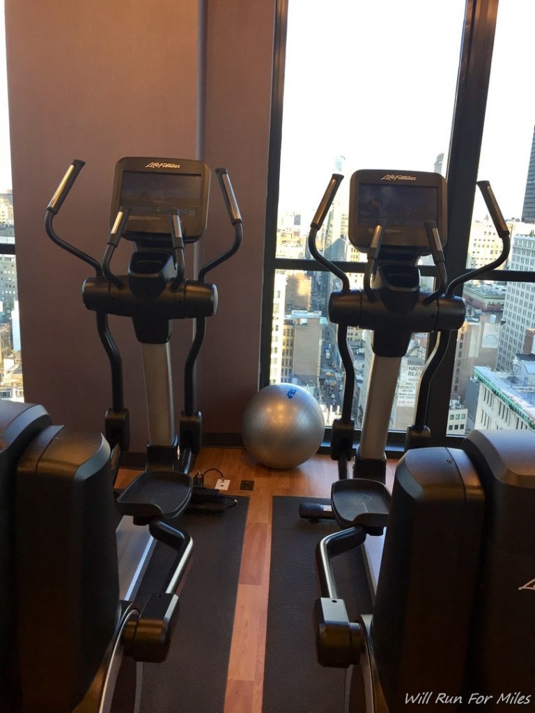 exercise machines in a room with a window and a view of a city