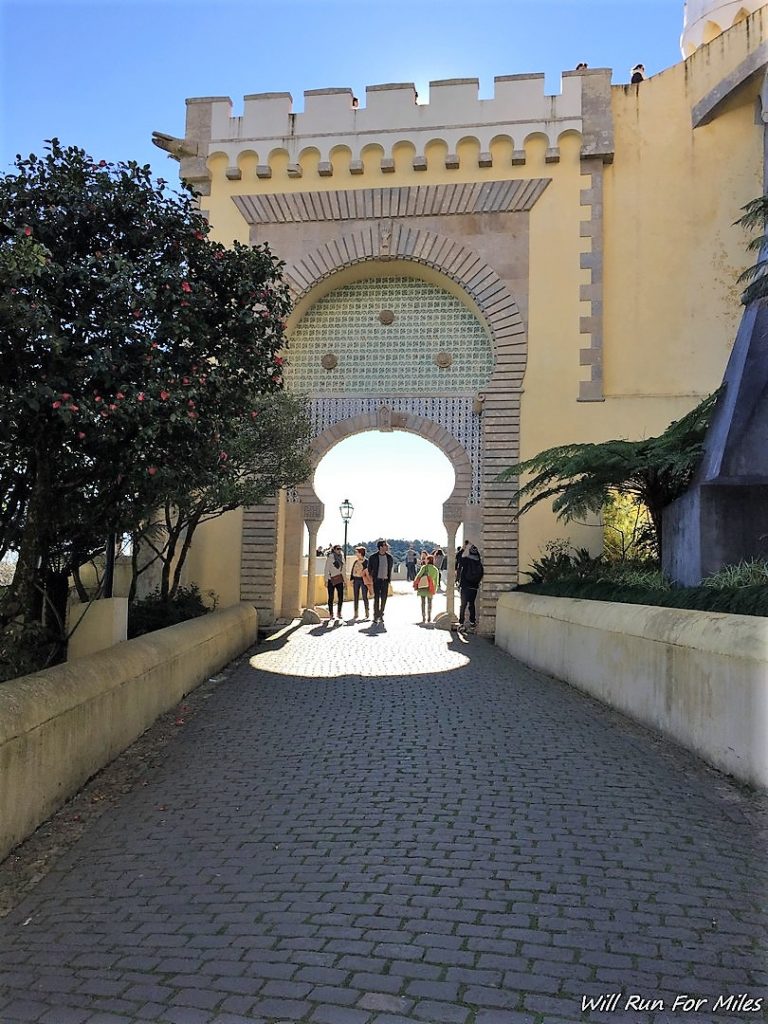 a group of people walking under a stone archway