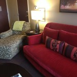 a living room with a red couch and a lamp