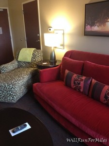 a living room with a red couch and a lamp