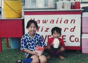 a couple of children sitting on grass eating ice cream