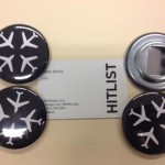 a group of black buttons with white airplanes on it next to a business card