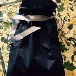 a black bag with a silver ribbon on a floral surface