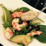a plate of salad with shrimp and avocado