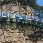 a group of people walking on a bridge over a cliff