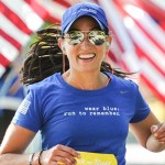 a woman running in a blue shirt and sunglasses