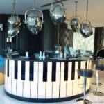 a bar with piano keyboard and silver pots from ceiling