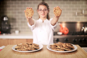 a woman holding cookies in front of plates of cookies