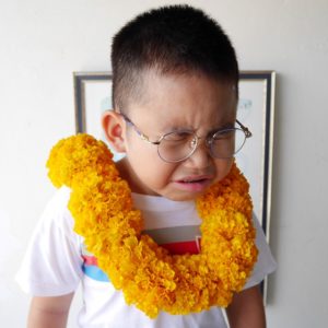 a child crying with a yellow flower necklace