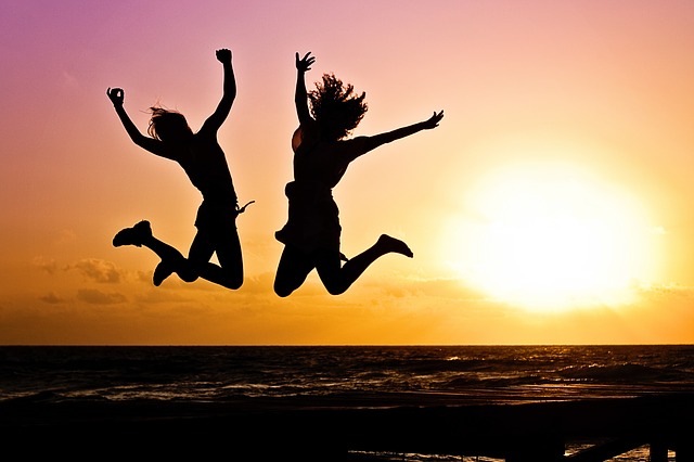 a silhouette of two women jumping in the air