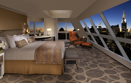 a bedroom with a large window overlooking a city