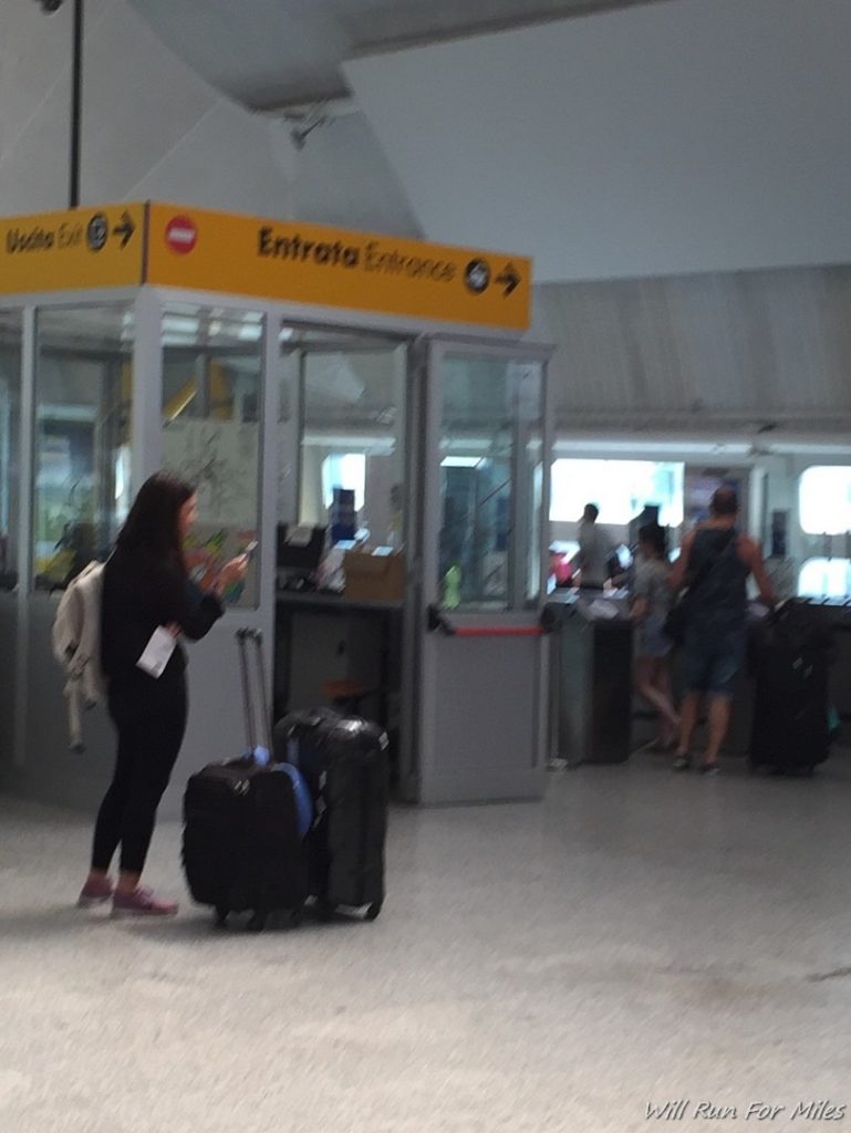 a woman standing with luggage in front of a glass booth