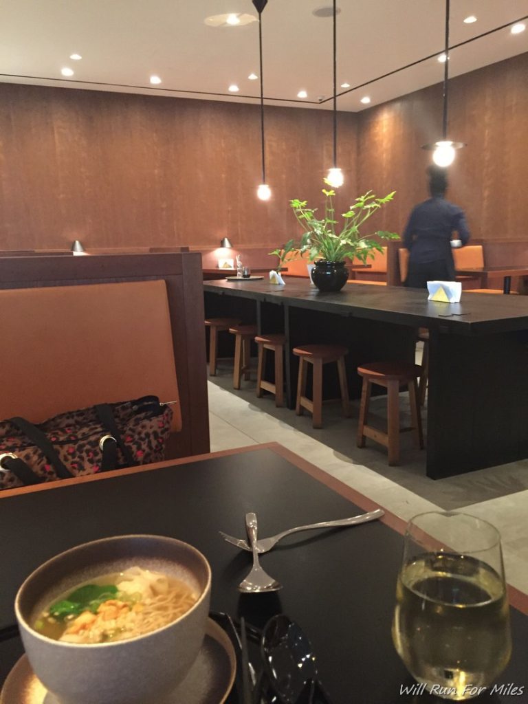 a table with a bowl of noodles and a plant in the background