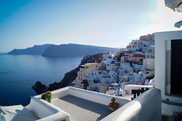 a white building with a body of water in the background with Santorini in the background