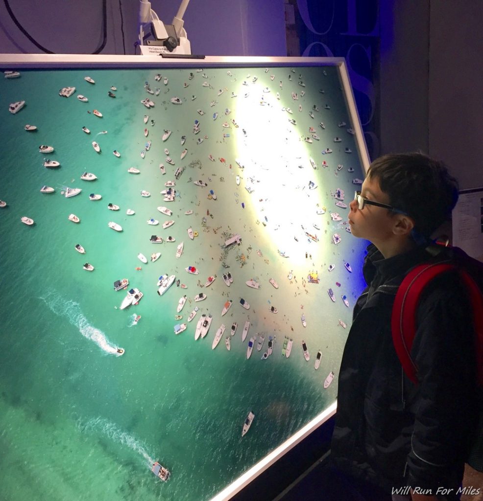 a boy looking at a large picture of boats
