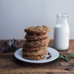 a stack of cookies on a plate next to a bottle of milk