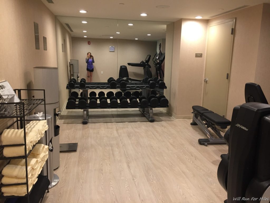 a room with a gym equipment and a woman standing in the background