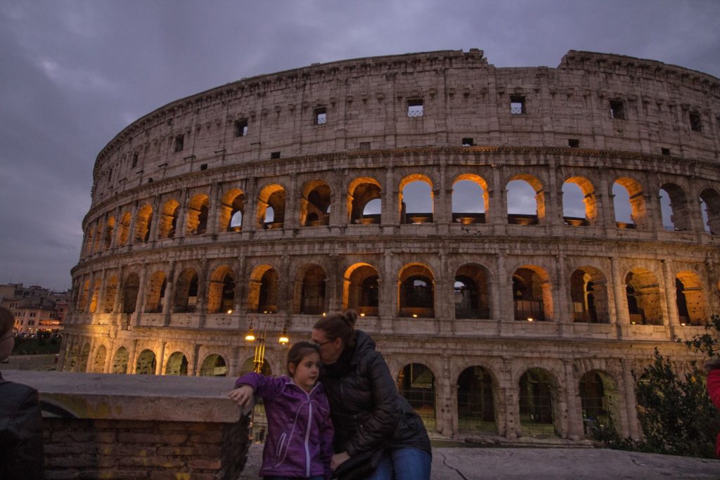 a woman and child posing for a picture in front of a large stone building with Colosseum in the background