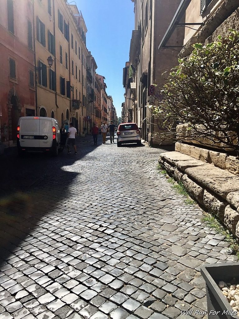 a stone street with cars and people on it