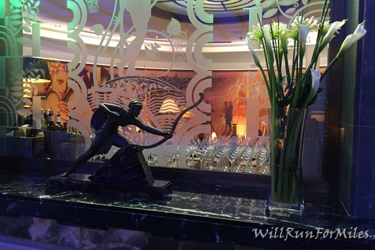 a statue of a man with a bow and arrow in front of a row of wine glasses