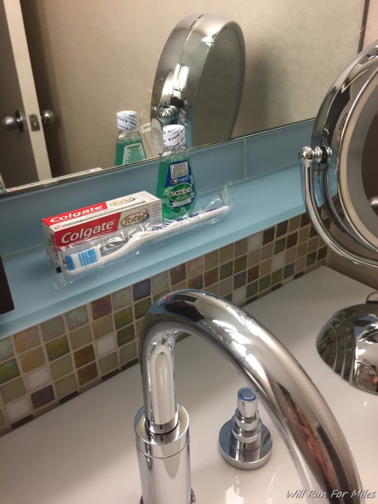 a bathroom sink with a mirror and a toothbrush and toothpaste