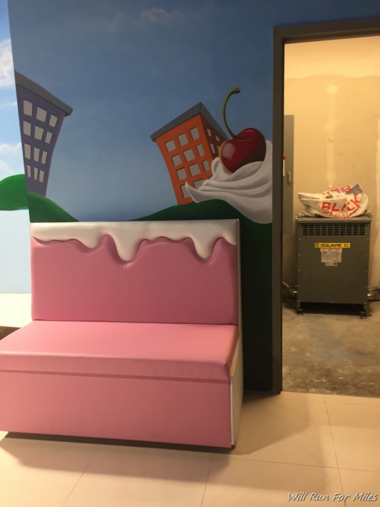 a pink bench with a painting on the wall