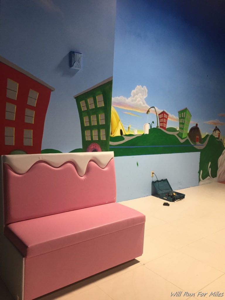 a pink bench in a room with a painted wall