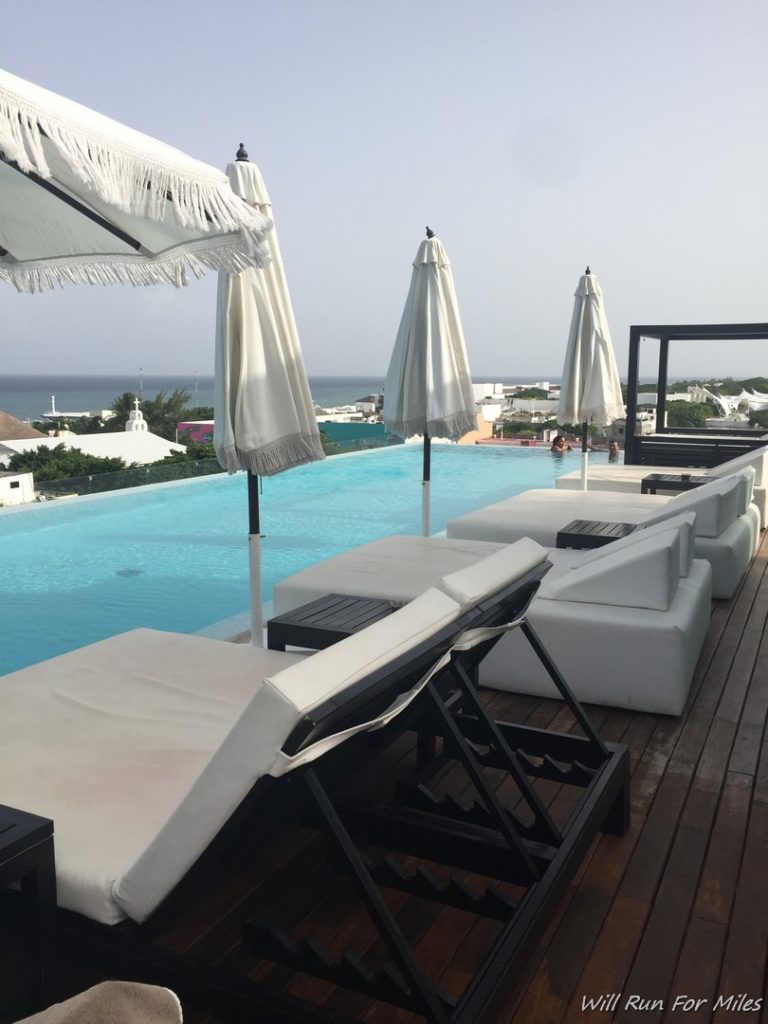 a pool with white umbrellas and lounge chairs