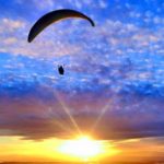 a person flying a parachute in the sky