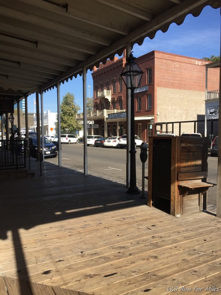 a wooden porch with a lamp post and a street in the background