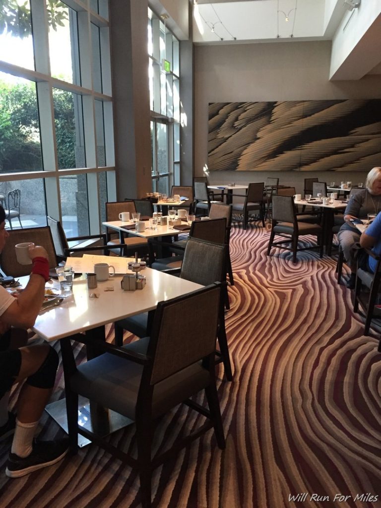 a group of people sitting at tables in a room with large windows