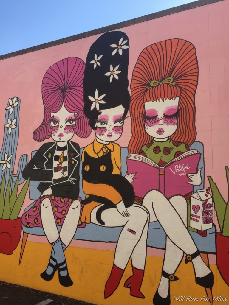 a mural of three girls sitting on a bench