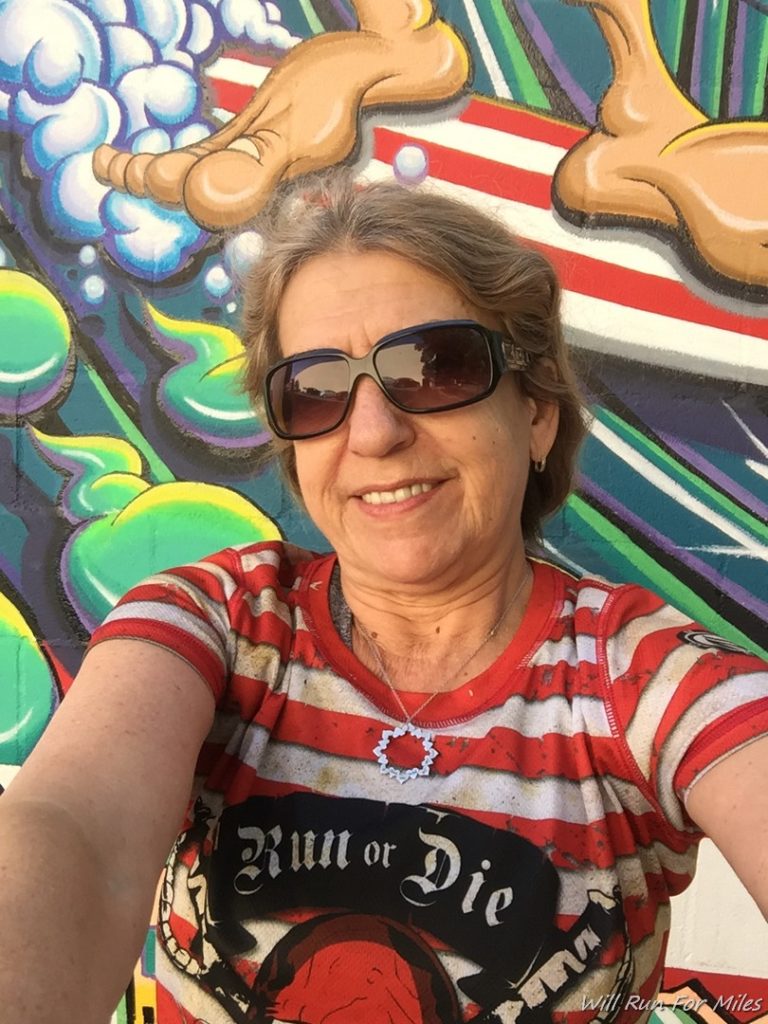 a woman taking a selfie in front of a graffiti wall