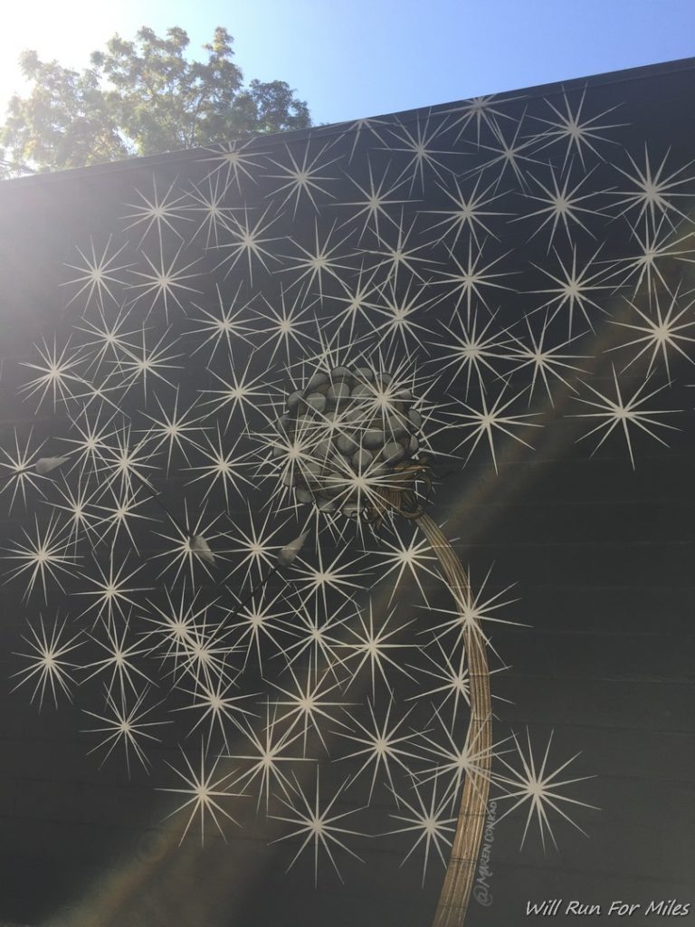 a wall with a painting of a dandelion