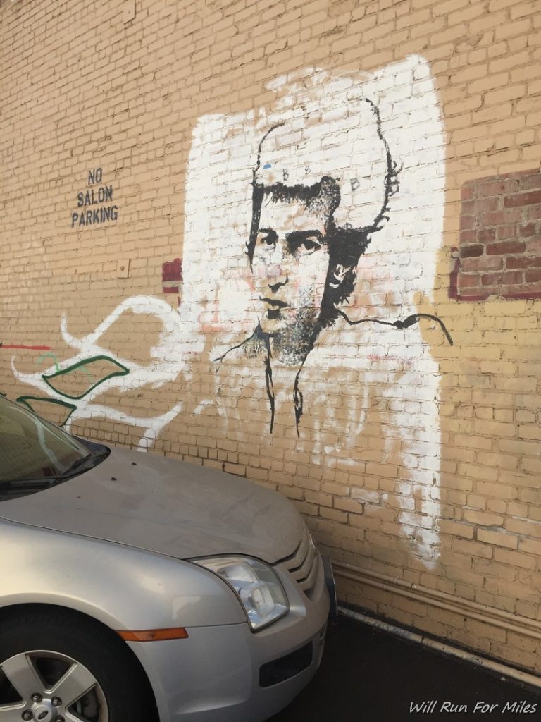 a car parked next to a wall with a painting of a man