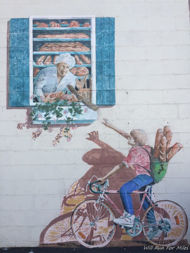 a mural of a boy on a bicycle and a woman in a window