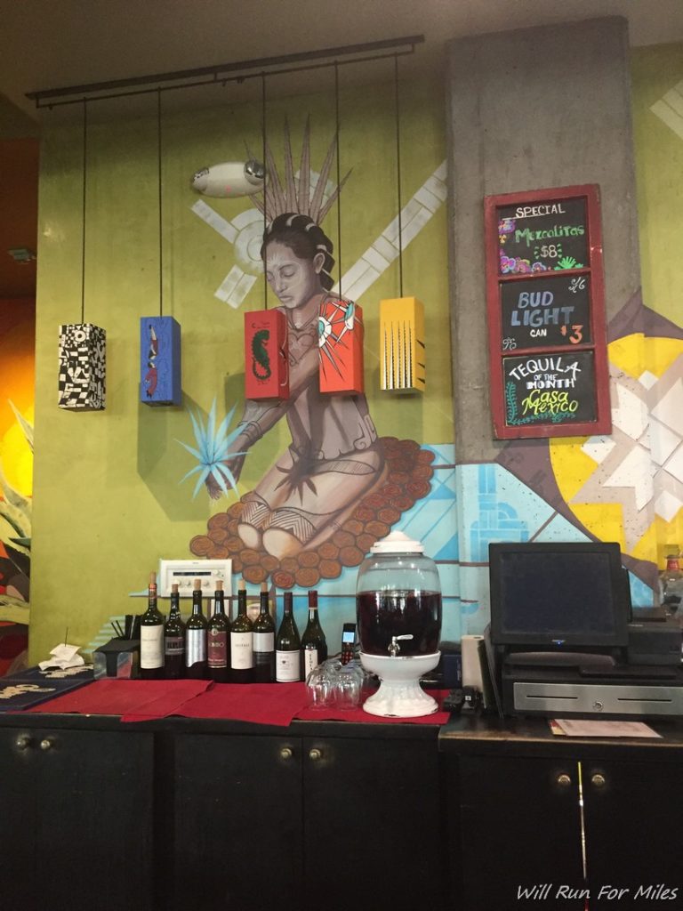 a bar with bottles of wine and a sign on the wall