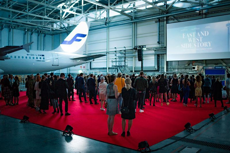 a group of people standing in a large room with a plane