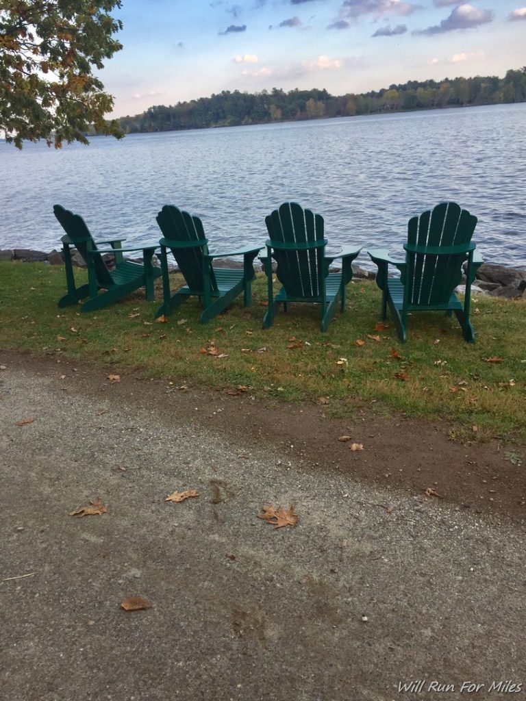 a group of green chairs by a body of water