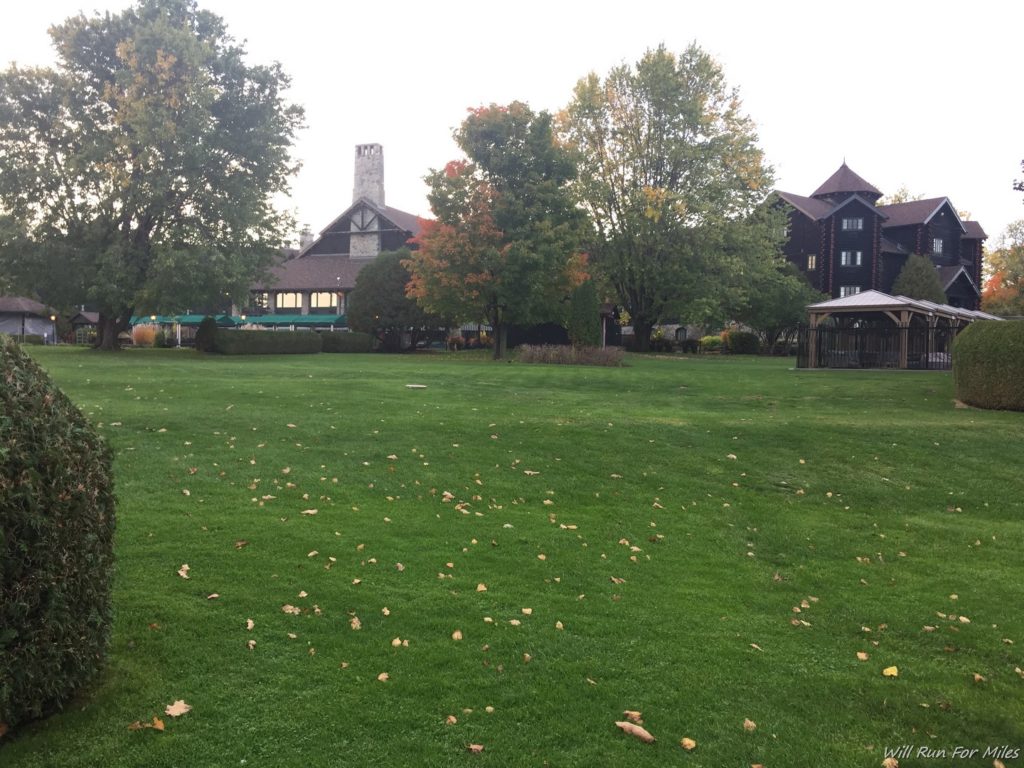 a large lawn with trees and buildings in the background