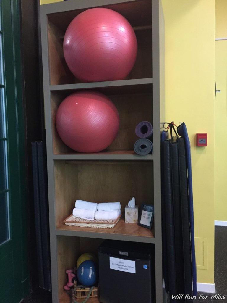 a shelf with exercise balls and yoga mats