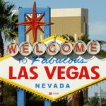 a large sign with palm trees with Welcome to Fabulous Las Vegas sign in the background