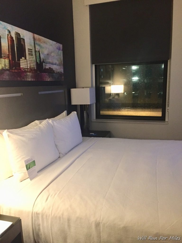 a bed with white sheets and a window