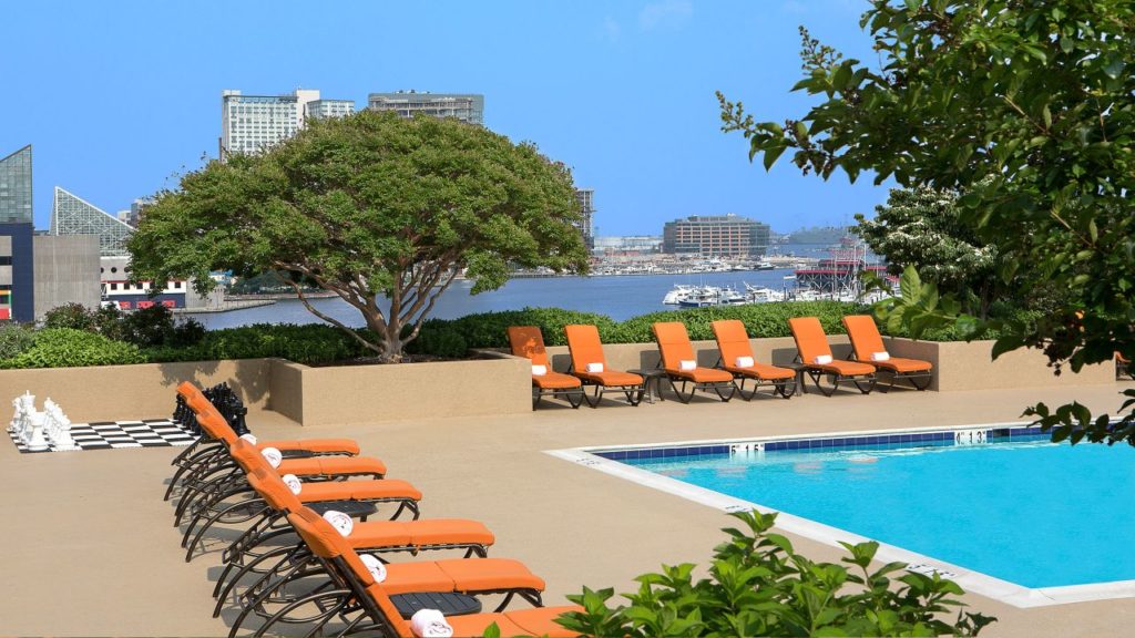 a pool with orange chairs and trees
