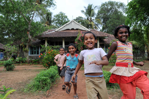 a group of children running in front of a house
