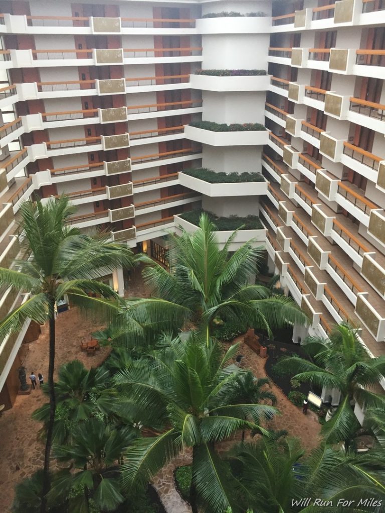 a courtyard with palm trees and a courtyard with people walking